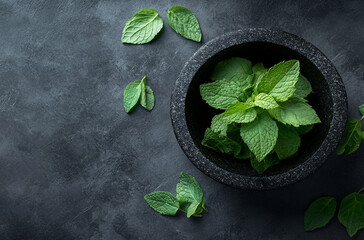 green mint leaves in the black stone mortar on a dark gray background