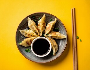 Japanese fried gyoza dumplings with soy sauce on yellow background