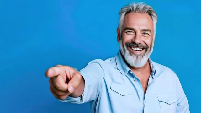 A handsome middle-aged man, isolated on an empty blue background, with a smile, a positive and confident expression, pointing his finger to the side