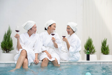 Middle-aged Asian women friends enjoy a pool party, holding glasses of wine and dancing. This vibrant scene radiates with friendship, relaxation, and the joy of sharing special moments together.
