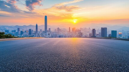 Obraz premium Empty asphalt road leading to a modern cityscape at sunset.