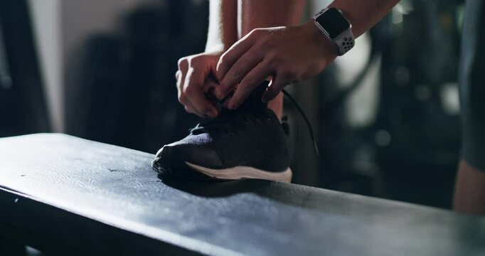 Person, hands and tying shoes at gym getting ready for workout, exercise or indoor training. Closeup of athlete tie shoe lace in preparation for cardio, run or fitness practice in health and wellness