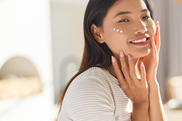 Healthy Skin Routine. Woman Applying Moisturizer With Joyful Expression, Capturing Beauty And Skincare Concepts In Natural Light. 