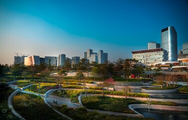 A park with a cascading waterfall and winding pathways nestled between skyscrapers in Shenzhen, China.