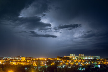 Lightning strikes in the night city among the menacing black clouds. Storm and thunderstorm