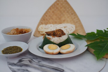 rice with meat, egg, crackers, sambal and noodles on a marble background