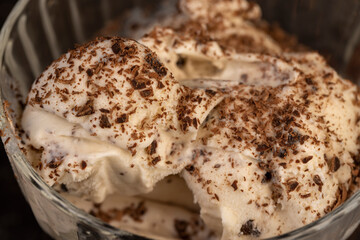 white creamy ice cream with pieces and crumbs of chocolate in a glass bowl