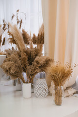 White vase with dried brown flowers on table