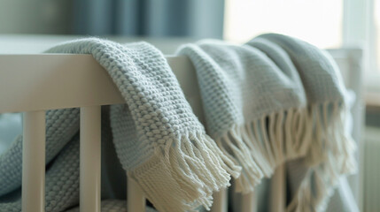 Close-up of a crib with a soft blanket draped over the side, focusing on the fabric and how it folds.