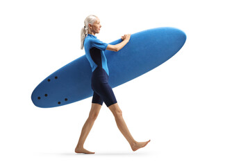 Woman in a wetsuit walking and carrying a surfboard