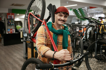 Portrait of satisfied client of bicycle hop carrying new vehicle for sport