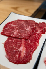 Korean Style Barbecue on plate in front of stainless grill. BBQ rare meat with soft focus