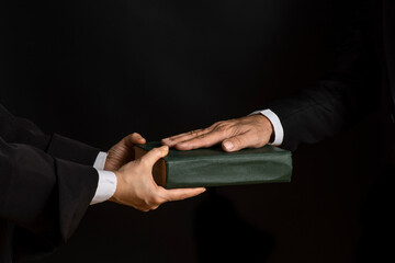 Hand on the Bible in court or the oath on the constitution book during the inauguration in...