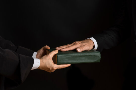 Hand on the Bible in court or the oath on the constitution book during the inauguration in parliament. Oath of Office.