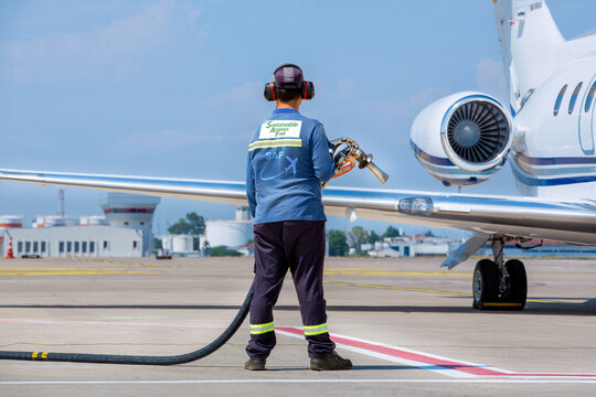 Sustainable Aviation Fuel (SAF) Technician refueling private jet with SAF at the airport.