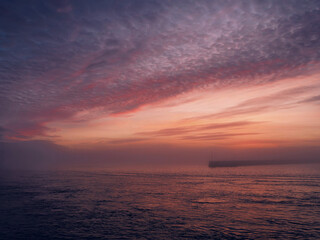 A yellow buoy sits in the ocean, surrounded by water. The sky is a beautiful mix of pink and purple hues, creating a serene and peaceful sunset atmosphere and mood. Nobody. Galway, Ireland.