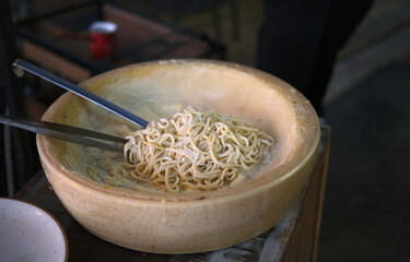 Preparing spaghetti in a wheel of Grana Padano cheese