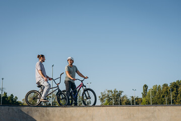 Obraz premium Two athletes having rest after riding at skatepark during summer morning day