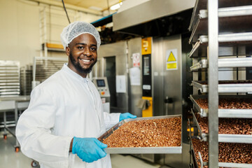 Portrait of happy multicultural food plant worker with baked peanuts smiling at camera.