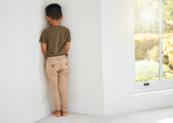 Back, child and sad in corner for discipline, behavior development and time out at home. Punishment, naughty kid and stand at wall for domestic abuse, fear and depression or anxiety for mistake