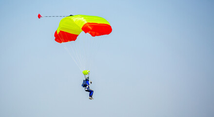 Skydiving. Flying parachutists against the background of the blue sky and mountains. Extreme sport and entertainment.