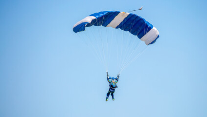 Skydiving. Flying parachutists against the background of the blue sky and mountains. Extreme sport and entertainment.