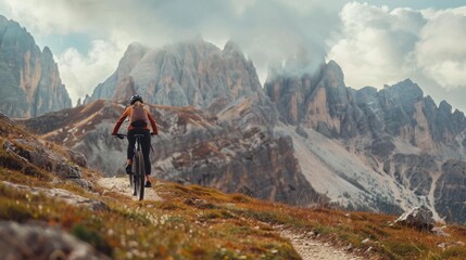 A cyclist rides through a breathtaking mountainous landscape under a cloudy sky, reveling in nature's beauty and solitude.
