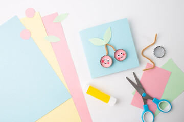 Scissors on paper in a child's craft project, showcasing cherry-themed card template in blue. Great for DIY and artistic education,