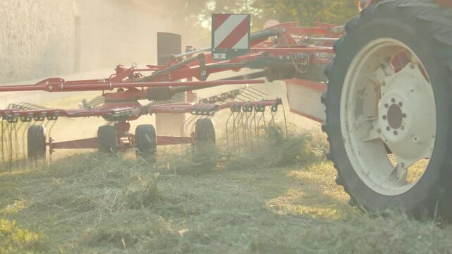 an agricultural tractor working in a field, creating rows of cut hay for agriculture in provence for the harvest