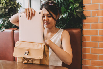 Asian woman putting her laptop computer into her backpack. Finished her work.