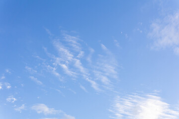 blue sky background with sparse cirrus clouds and moon