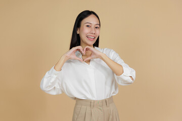 Smiling Woman Forming Heart Shape with Hands, Beige Background