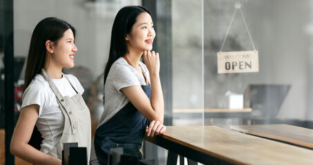Small startup business owner concept. two successful young baristas women standing in bar counter...
