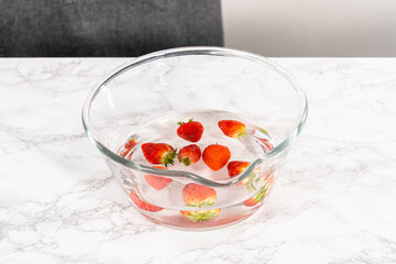 Preparing Strawberries in a Glass Mixing Bowl with Water