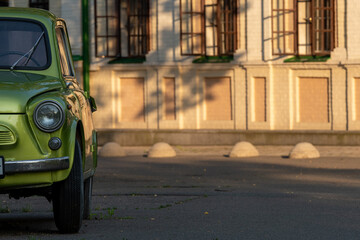 Old retro green car detail in the background of the classic building with the shadows during the golden hour in Kyiv botanical garden, Ukraine.