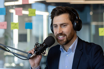 Man wearing headphones speaks into microphone in office. Engages modern communication setup, ideal...