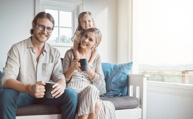 Fototapeta premium Portrait, happy and parents with child on sofa for bonding, loving relationship and relax together in morning. Family, coffee and mom, dad and girl on couch for love, laugh and embrace in living room