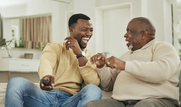 Senior father, son and remote on sofa with laughing for funny football match, esports or bonding in home. Happy family, black people and relax on couch with watching television, talking or sport show - Powered by Adobe