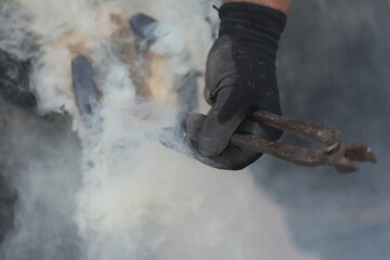 Farrier fits the horseshoe on the horse's hoof. Equestrian life outdoors at animal farm