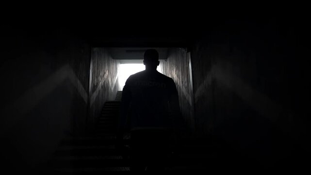 Silhouette of man walking on stairs out of a tunnel.High contrast 4k