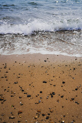 Sea Waves Crashing on Beach Sand with Stones and shells on the shore