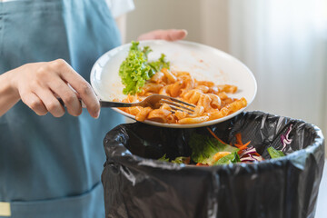 Compost from leftover food in the meal in household, female hand holding left over meal use fork scraping waste, rotten vegetable throwing away into garbage, trash or bin. Environmentally responsible