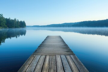 Fototapeta premium A wooden pier extends horizontally over a calm lake reflecting the clear sky