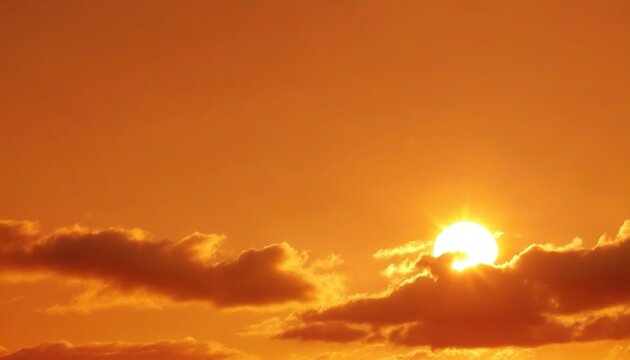 Orange sky with sun and clouds during hot summer weather