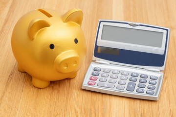 Saving money with a gold piggy bank with calculator on a desk