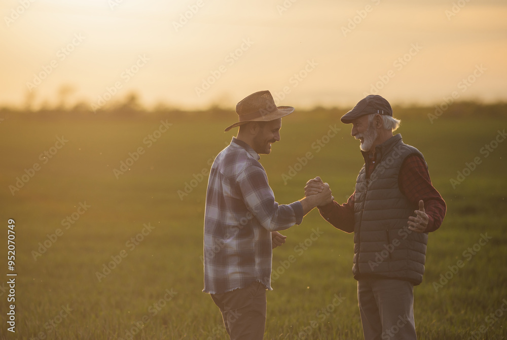 Wall mural Two farmers shaking hands in wheat field