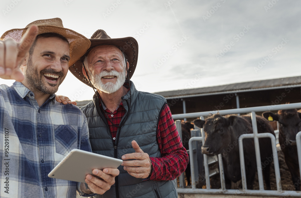 Wall mural Two farmers using tablet on cattle ranch