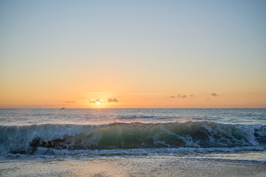Waves crashing into beach at sunrise or sunset