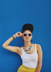 Woman, portrait and sunglasses with fashion in studio for summer style on a blue background. Young female person, gen z model or hipster with eyewear, jewelry or stylish accessories on mockup space