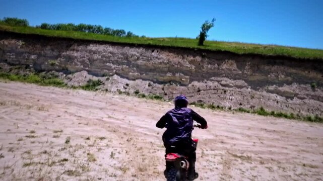 Aerial view from FPV drone. Next shot of a professional motocross rider riding his FMX motorcycle on extreme off-road terrain